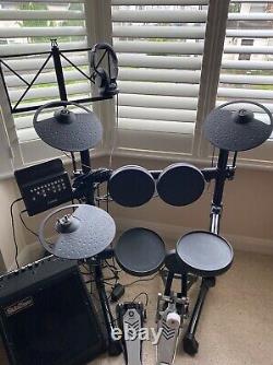 Yamaha electronic drum kit with rolled headphones, amplifier, and a music stand
